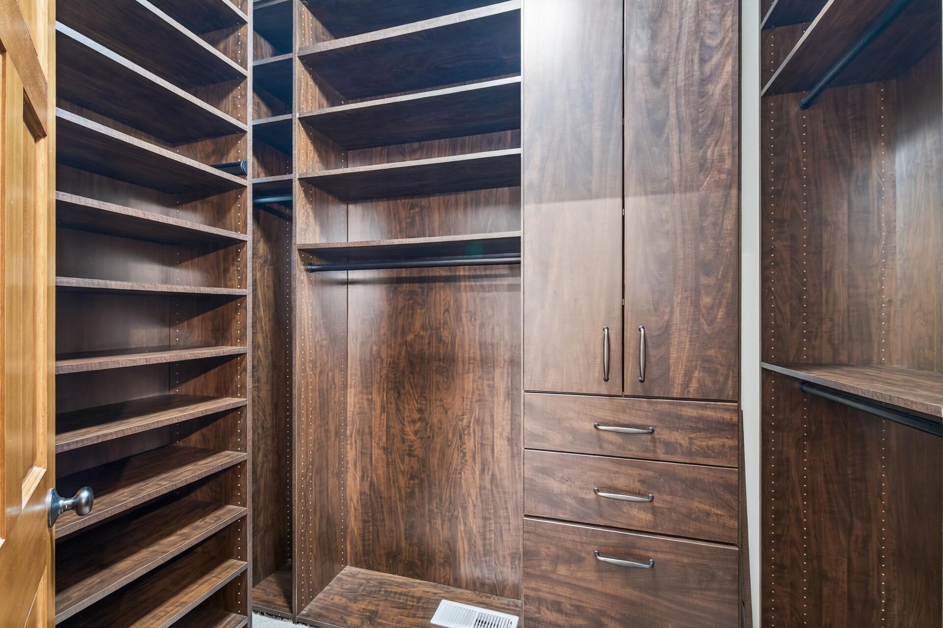 Custom walk-in closet with built-in shelving, drawers, and hanging space for optimal organization. Thoughtfully designed to maximize storage and functionality.