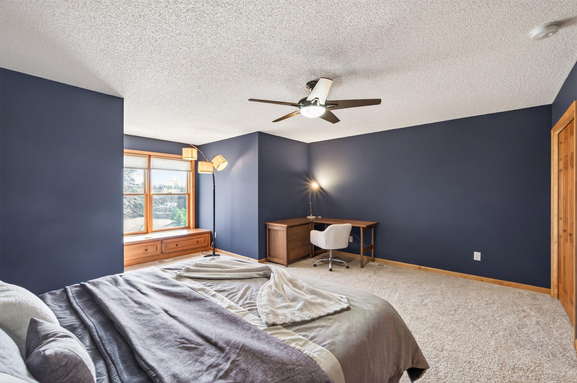 View of the primary bedroom showcasing generous layout, modern ceiling fan, and flexible space for a seating or workspace area.