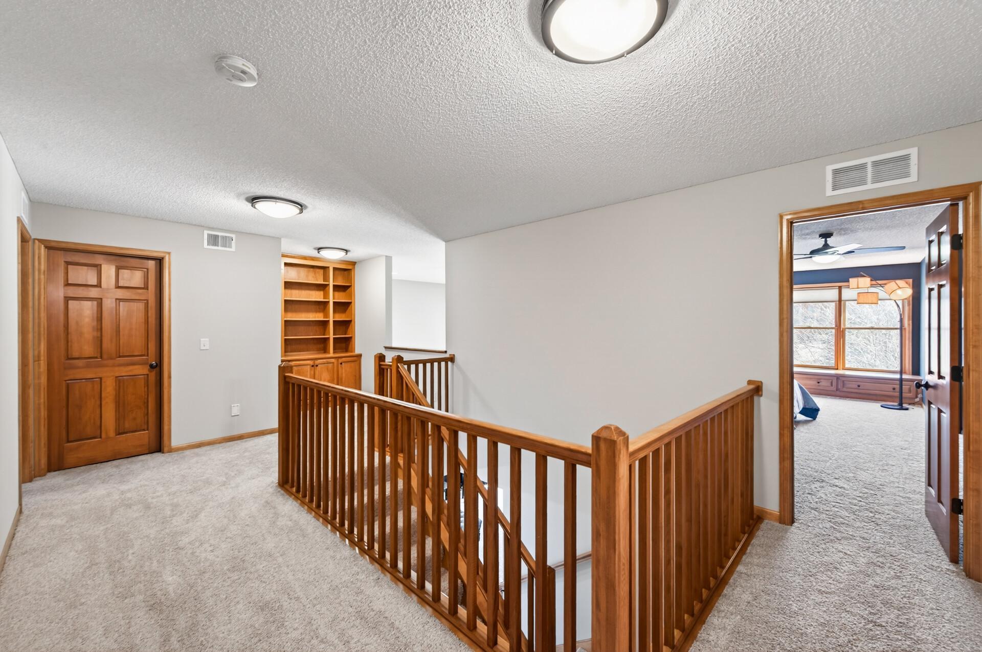 Spacious upper-level loft area with open railing overlooking the lower level and built-in shelving for added storage. A versatile space perfect for a reading nook, workspace, or additional living area.