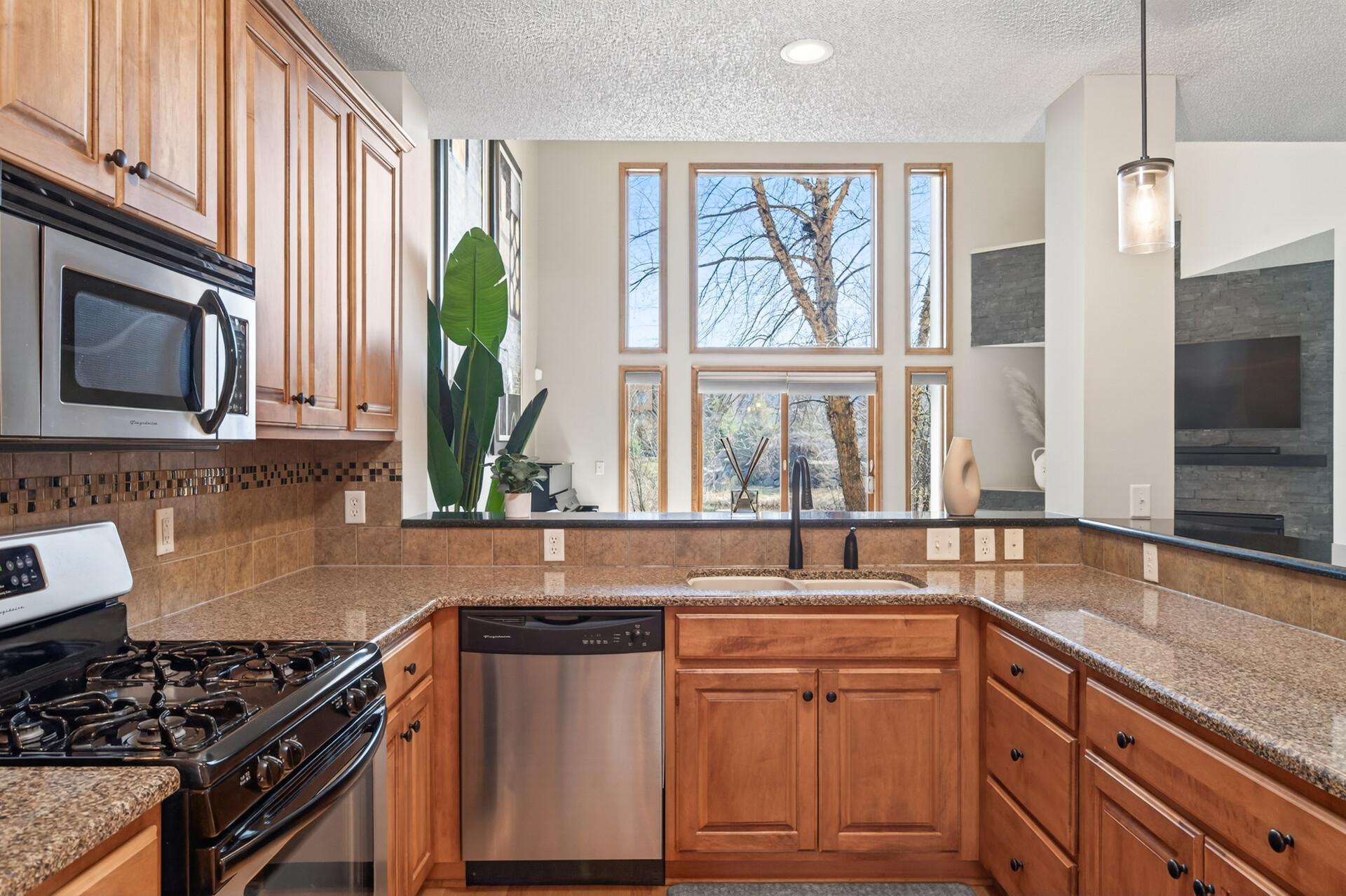 Kitchen with elevated sightlines into the living room, creating an open and connected feel. Large windows bring in natural light and enhance the overall space.