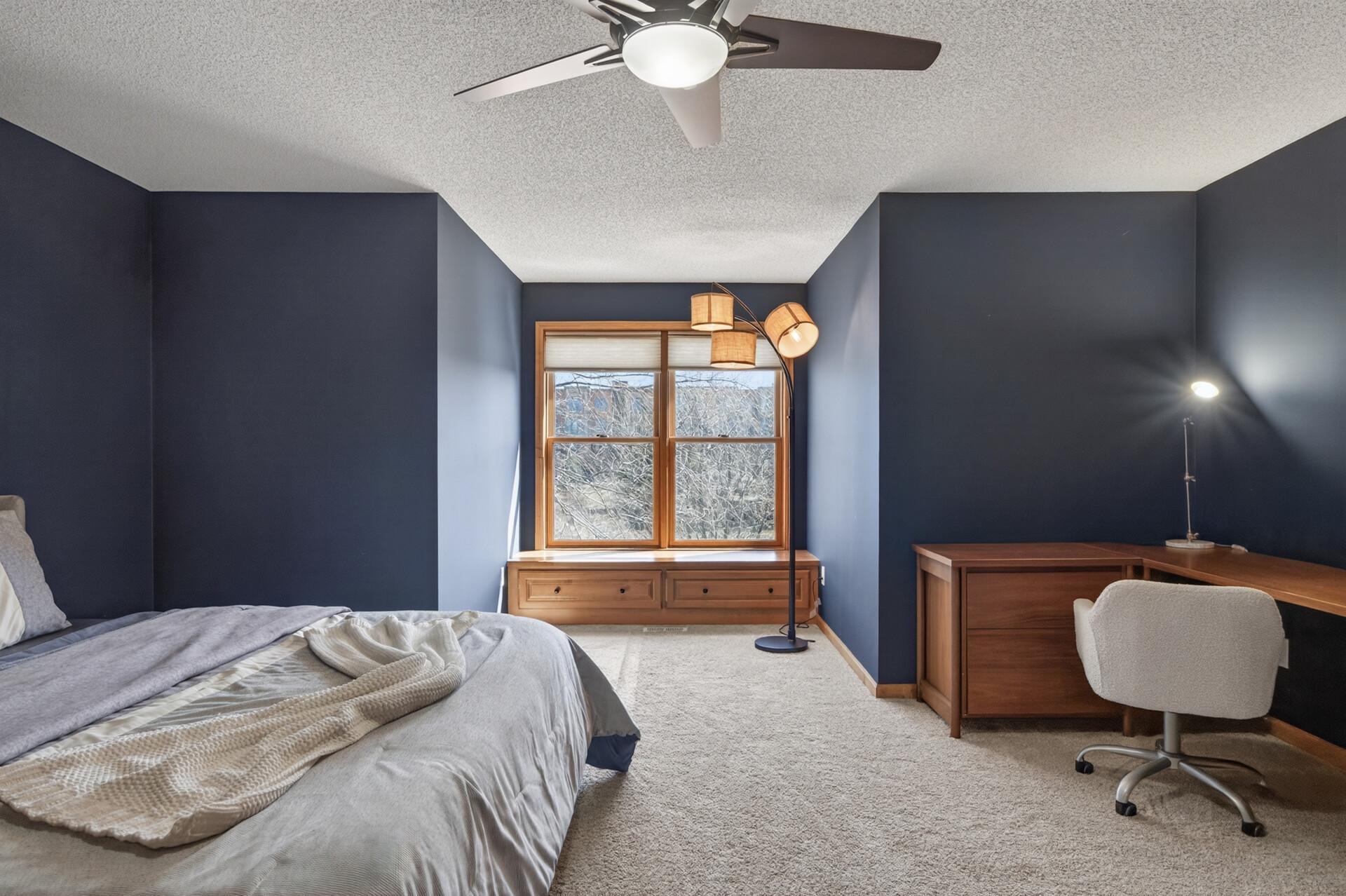 Alternate view of the primary upper-level bedroom showcasing generous layout, modern ceiling fan, and flexible space for a seating or workspace area.