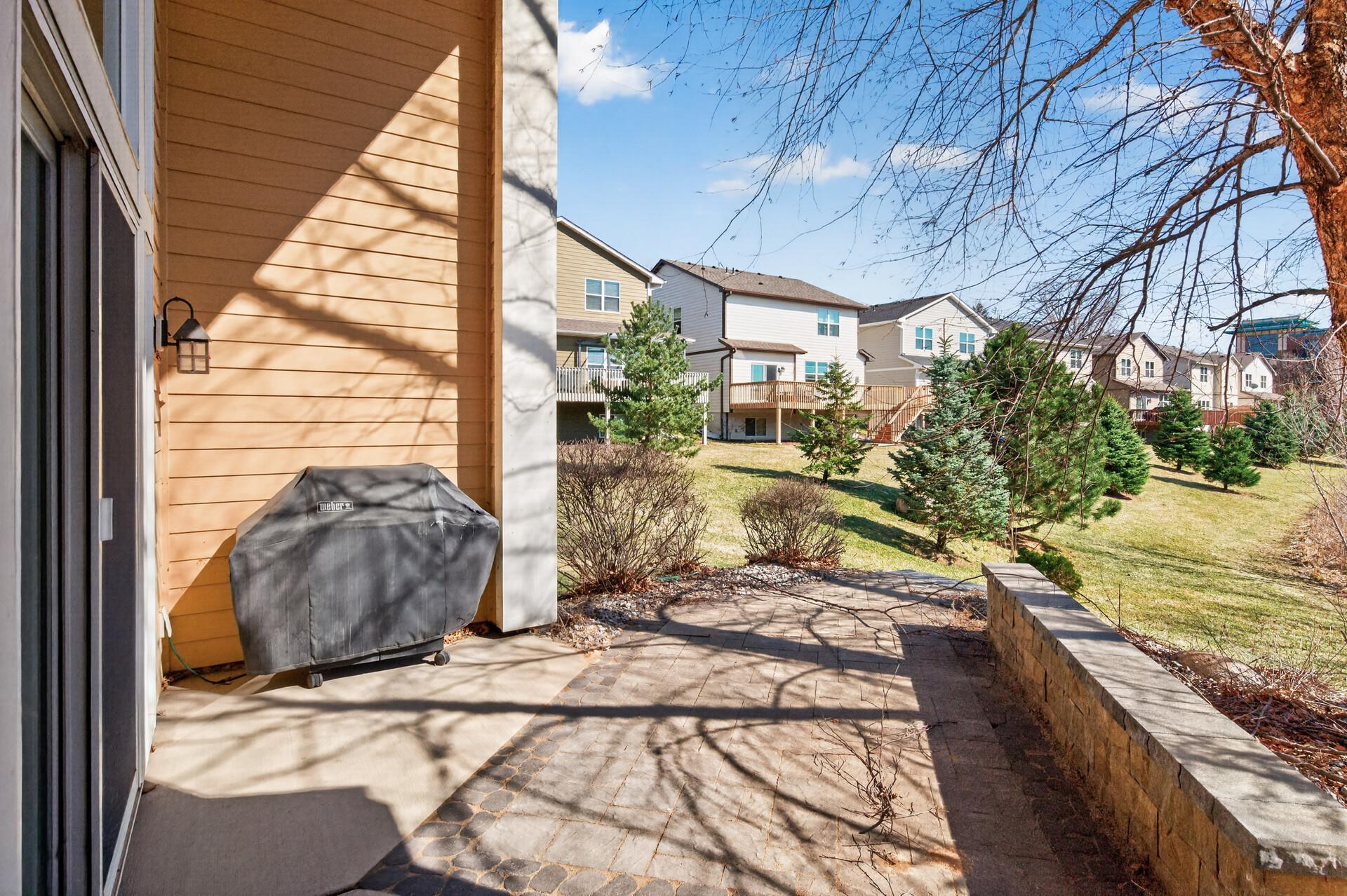 Expanded patio view featuring privacy elements and direct access to green space, creating a seamless indoor-outdoor connection.