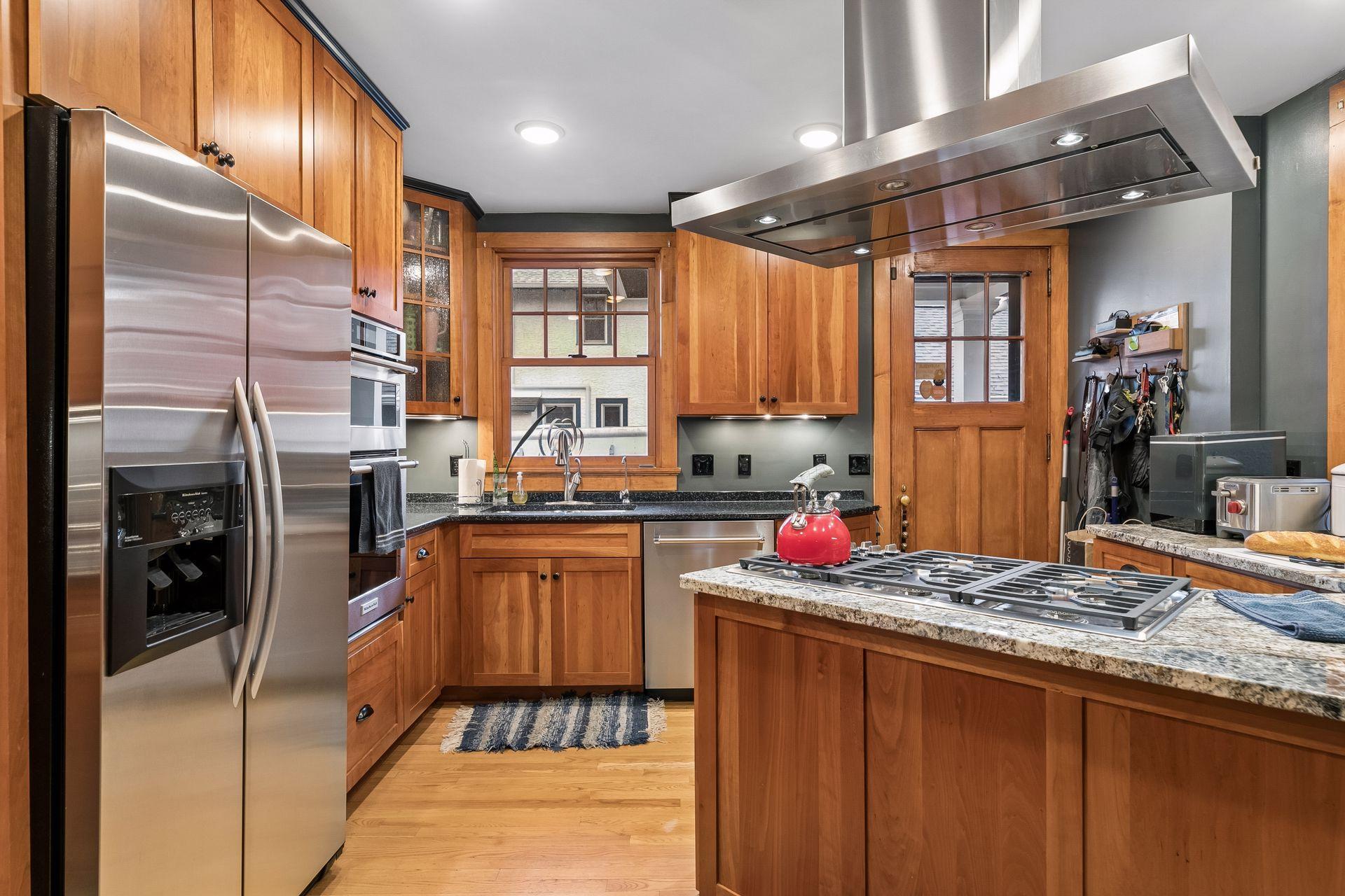 State of the art kitchen with commerical vent fan over cooktop. All stainless steel appliances - disposal under sink - door to backyard