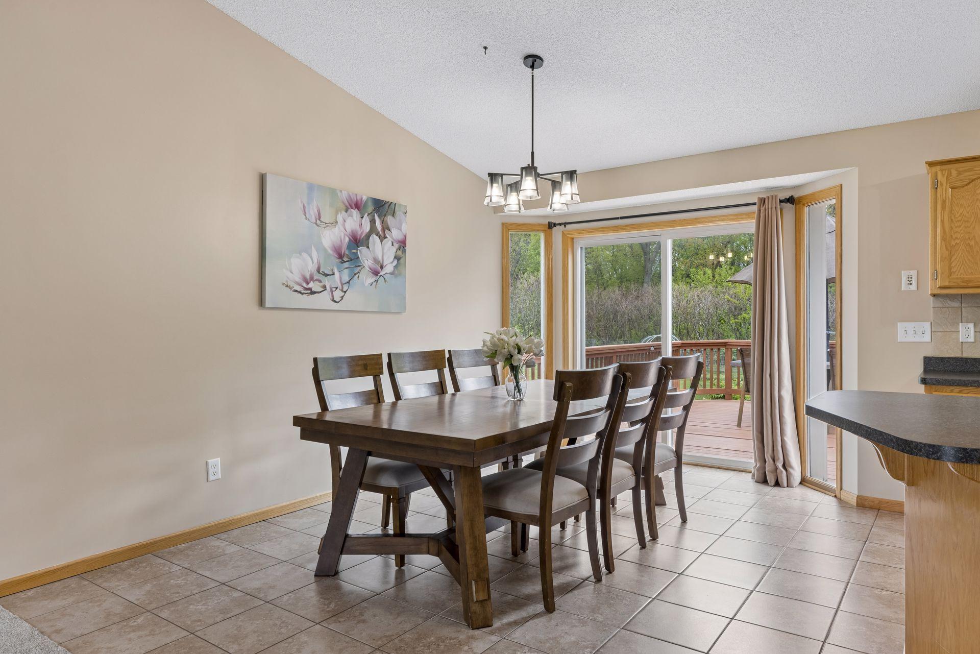 Bright and airy dining area with vaulted ceilings, updated lighting, tile flooring and direct access to the expansive backyard deck.