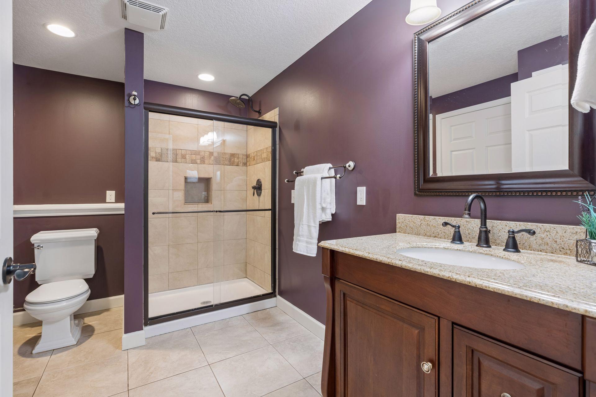 Beautifully updated lower-level 3/4 bathroom featuring a tiled shower with glass doors, granite vanity, tiled flooring and stylish finishes throughout.