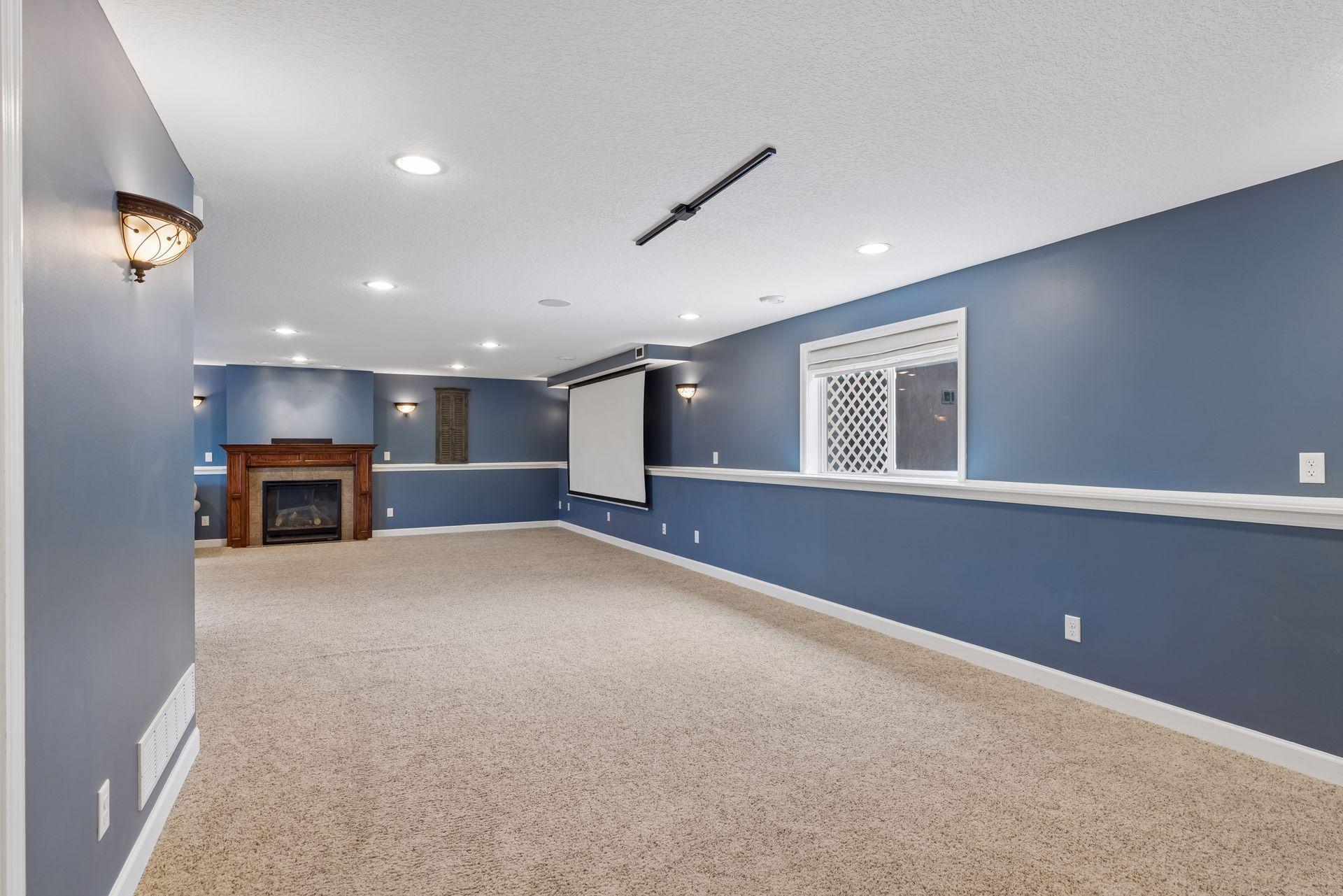 Expansive lower-level family room featuring a cozy gas fireplace, projector/theater setup, surround sound, and endless space for movie nights, game tables, entertaining, workouts, or a home office.