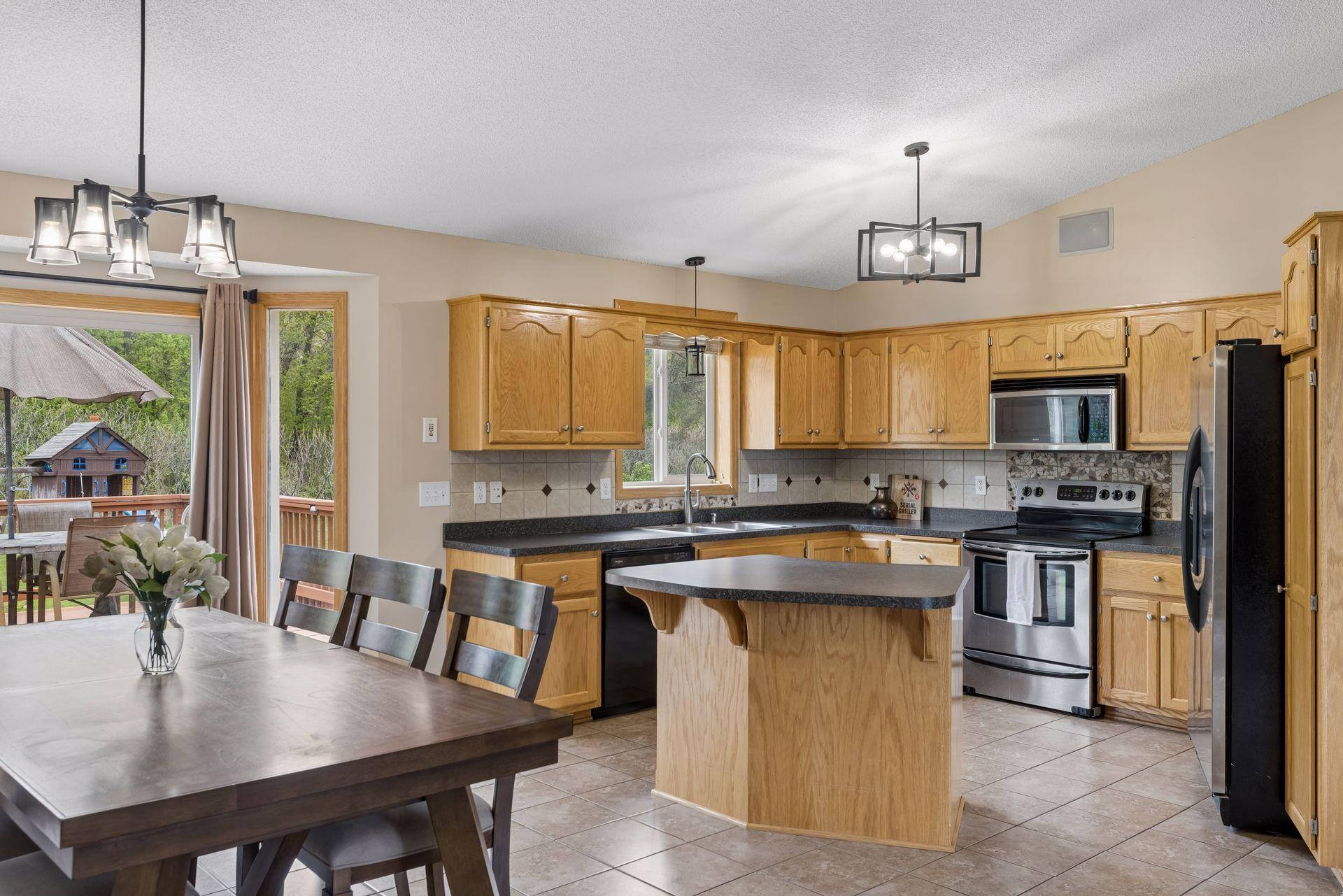 Spacious open-concept kitchen and dining area featuring vaulted ceilings, abundant cabinetry, a center island, and seamless access to the backyard deck.