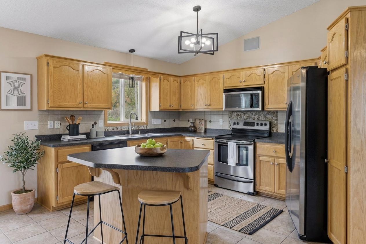 Spacious and functional kitchen featuring updated light fixtures, under-cabinet lighting, decorative backsplash accents, a center island and a large window. *Virtually staged to show design options.