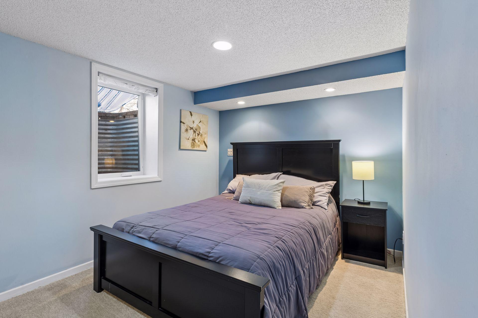 Spacious lower-level bedroom featuring egress window, recessed lighting, and a cozy, private feel.