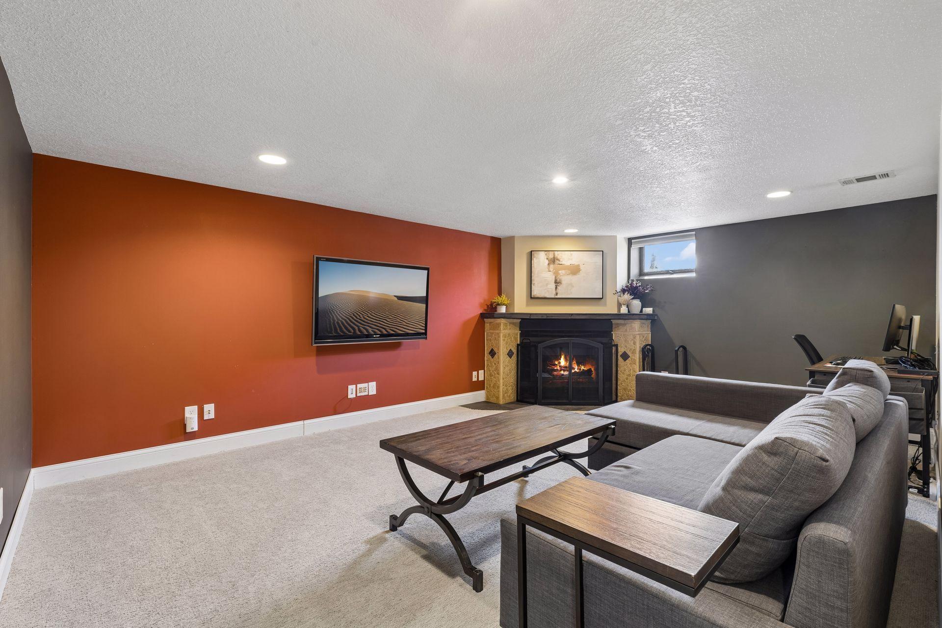 Spacious lower-level family room with cozy fireplace, recessed lighting, and room for relaxing or entertaining.