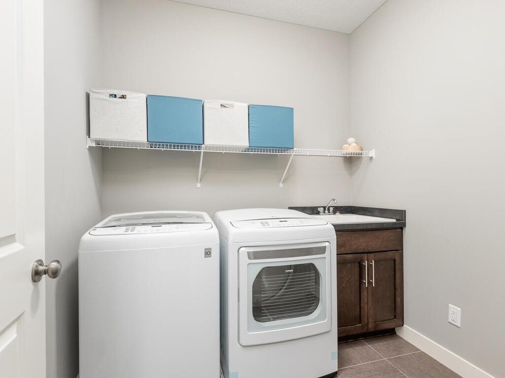 Laundry room with utility sink, cabinetry, and shelving for added organization.