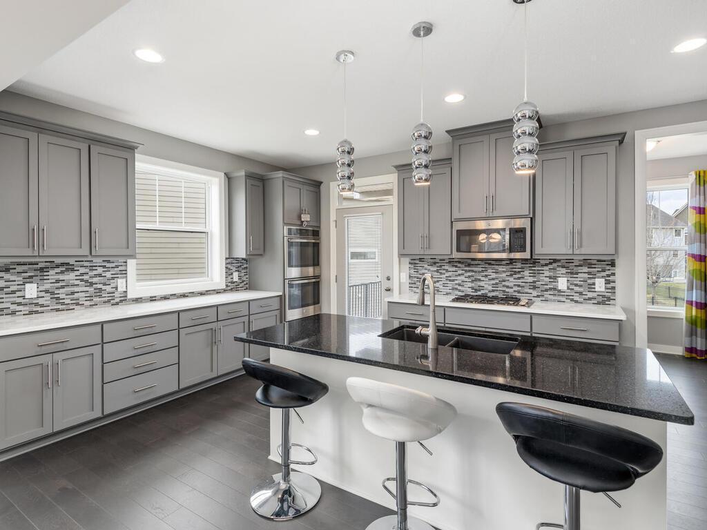 Spacious kitchen featuring abundant cabinetry, tile backsplash, and double wall ovens.