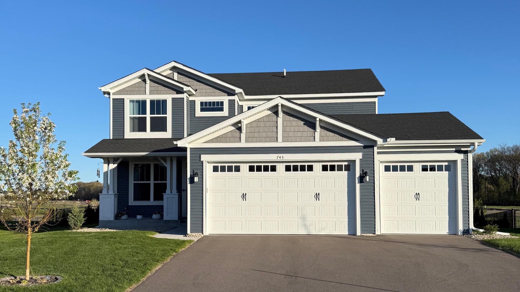 Charming two-story exterior featuring a spacious front porch and a desirable three-car garage.