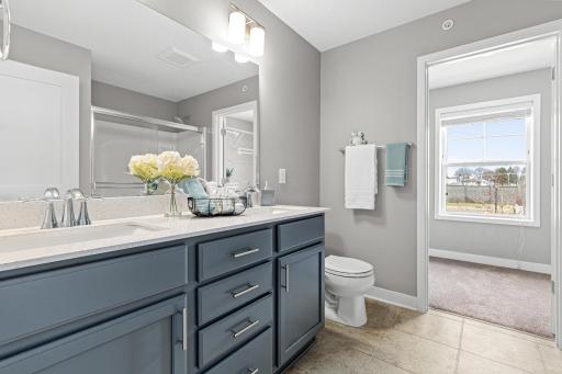 Spacious primary ensuite featuring a dual vanity and modern finishes. This private retreat provides direct access to the walk-in closet, which includes a window for refreshing natural light and added ventilation.
