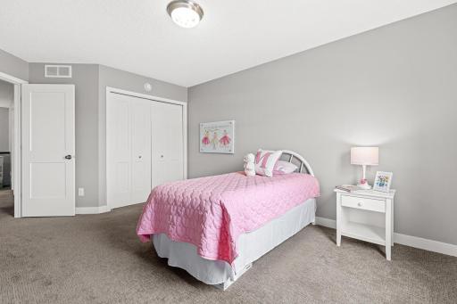 Bright second bedroom featuring a spacious double-door closet for ample storage. The view toward the doorway highlights the seamless transition into the versatile loft, keeping the upper-level living space feeling open and connected.