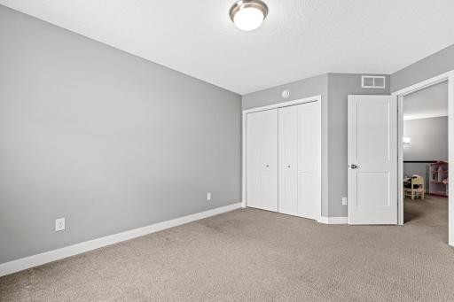 Bright third bedroom featuring a spacious double-door closet for storage. The view toward the doorway highlights the seamless transition into the versatile loft, keeping the upper-level living space feeling open and connected.