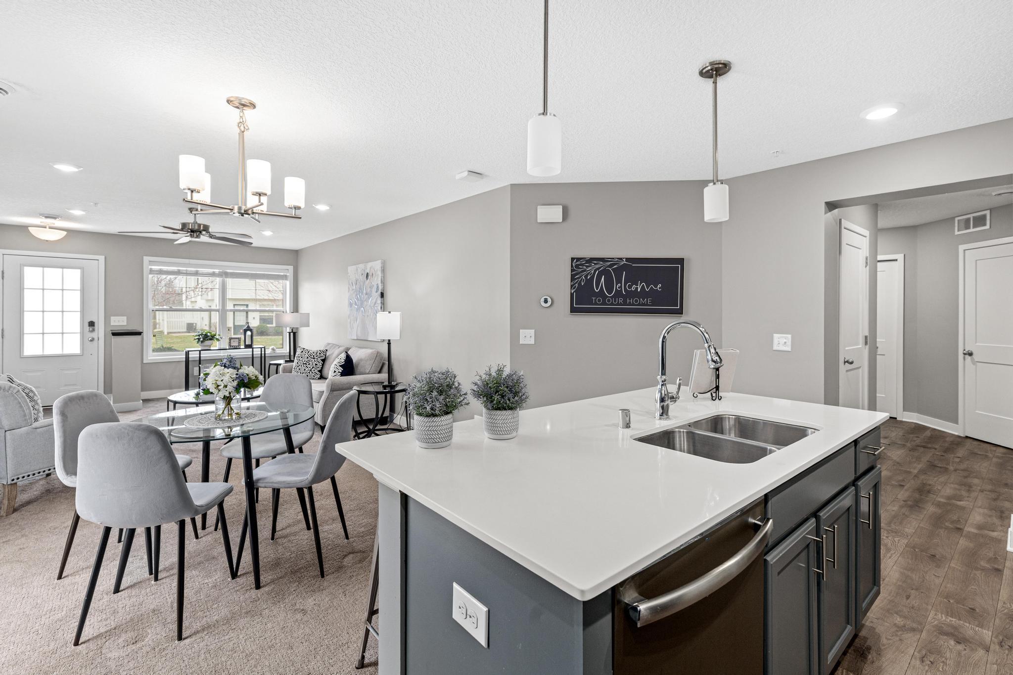 This perspective highlights the living room and hallway leading to the garage, powder room, and utility room. Open sightlines ensure a large, connected feel, perfectly capturing the benefits of this modern end-unit layout.