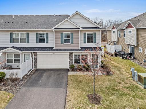 View of the double garage and driveway with guest parking available. The layout features a yard and a glimpse of the side patio, offering ample parking and functional outdoor space.