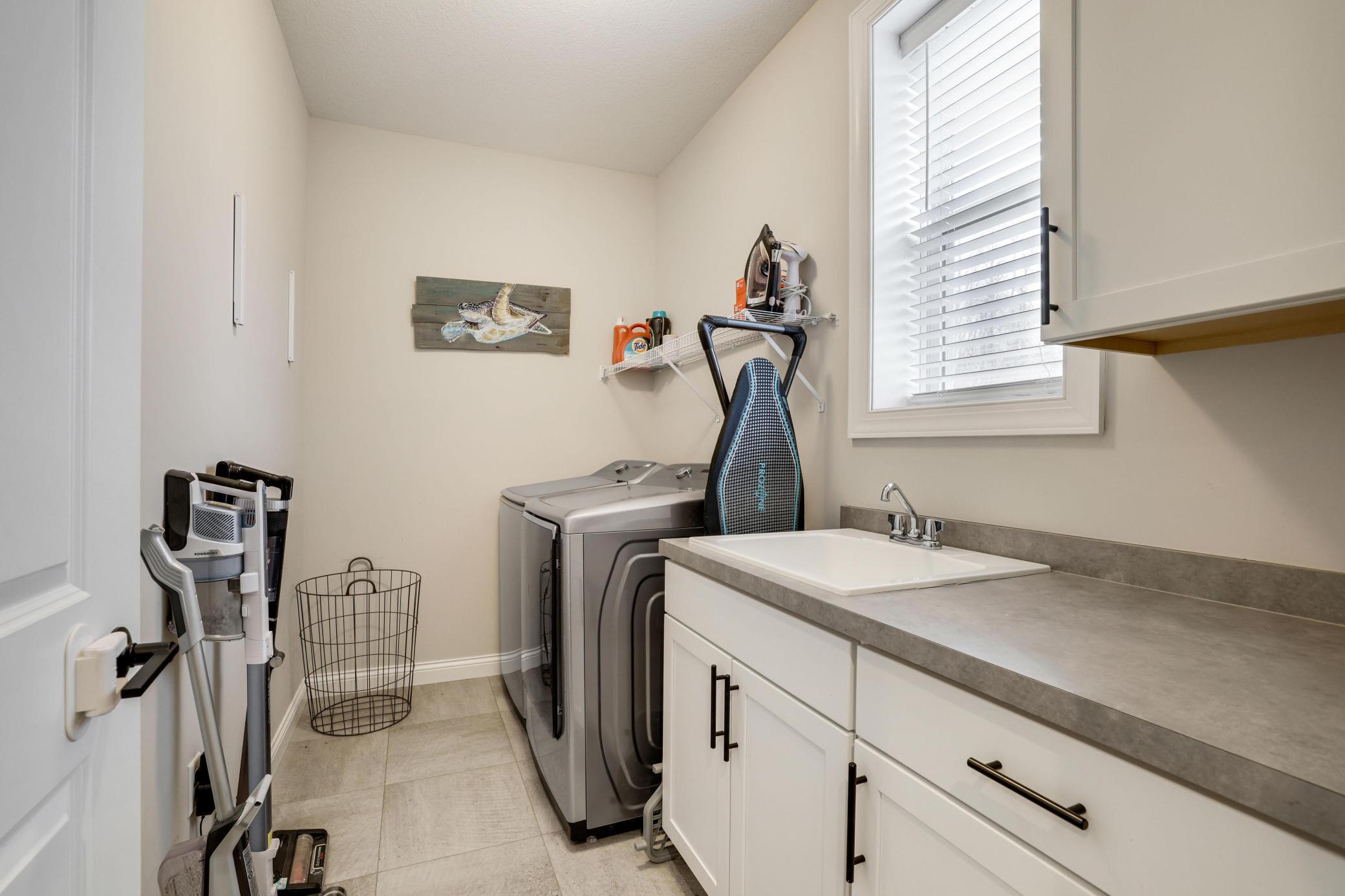 Convenient laundry off the mud room has cabinets and a laundry tub