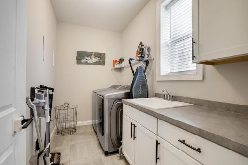 Convenient laundry off the mud room has cabinets and a laundry tub