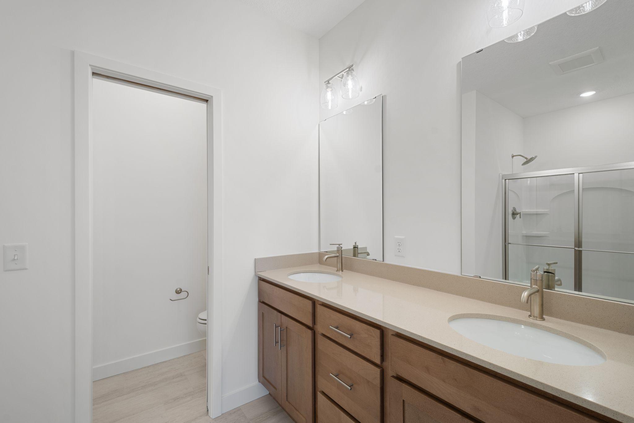 Owner's bathroom with double sinks, enclosed toilet area with linen closet, and shower