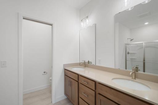 Owner's bathroom with double sinks, enclosed toilet area with linen closet, and shower