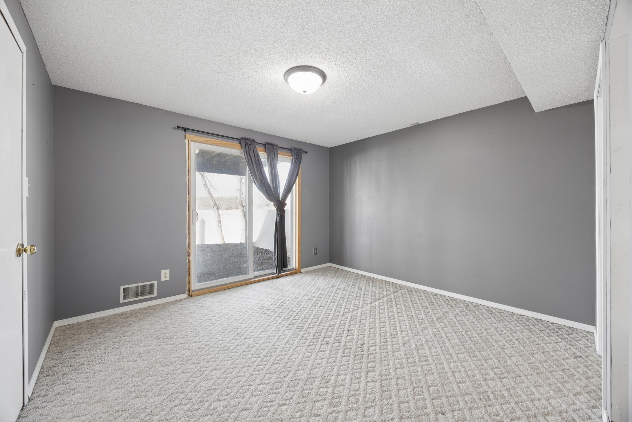 Lower level bedroom featuring a patio door that walks out to the patio and lake views, complete with a walk-in closet and convenient access to the bathroom.