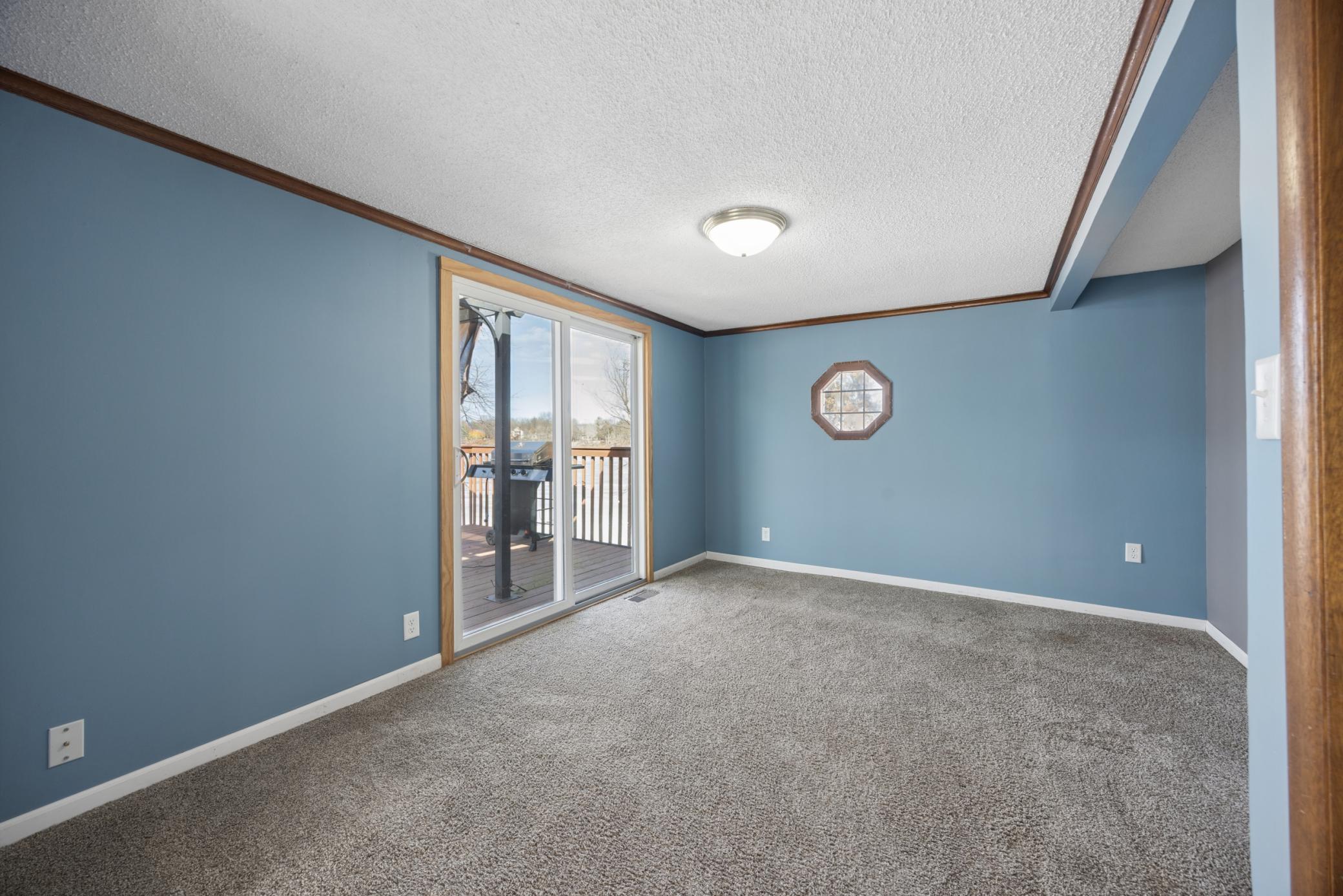 Cozy living room just off the dining area featuring a patio door that brings in natural light and opens to the deck with lake views.