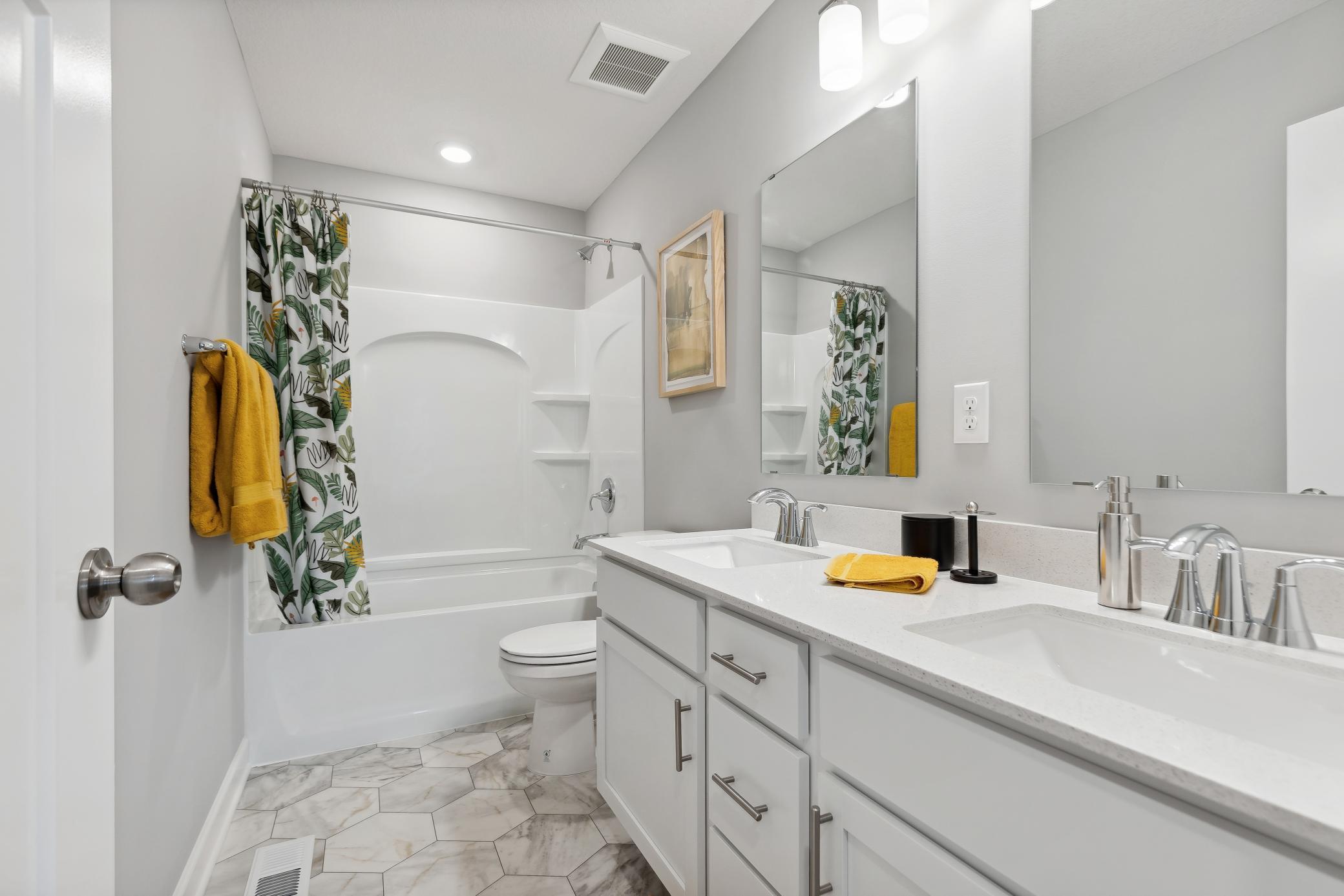 This full-sized bathroom on the second floor conveniently features dual sinks and a shower-tub combination.