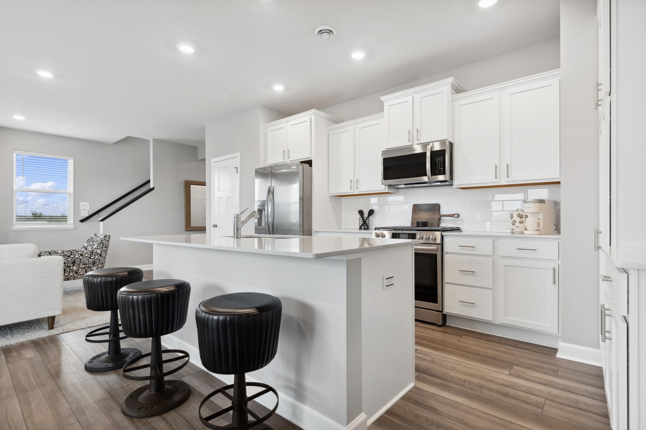 The modern kitchen features a flexible open layout with a center island, brand-new stainless steel appliances and ample cabinetry storage.