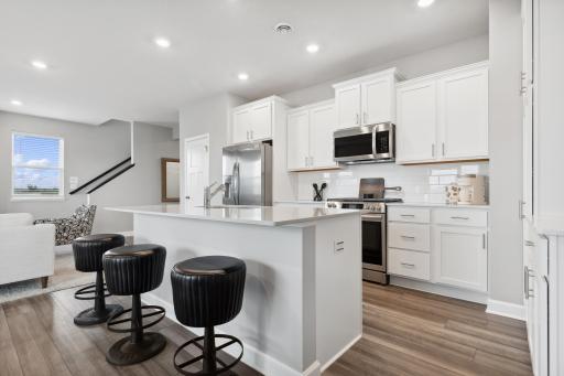 The modern kitchen features a flexible open layout with a center island, brand-new stainless steel appliances and ample cabinetry storage.