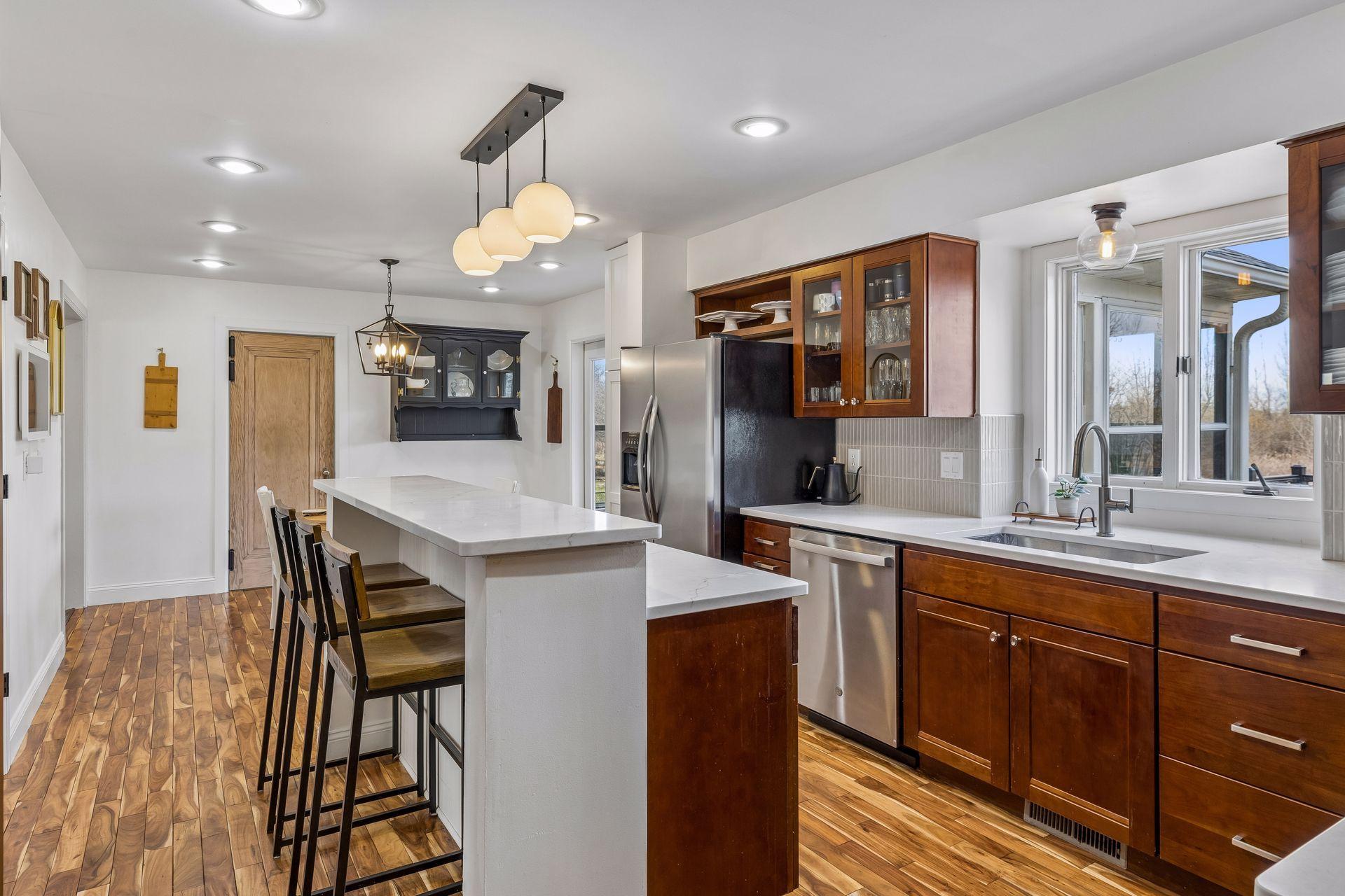 Spacious kitchen with lots of natural light, more of the beautiful hardwoods, quartz counters and a new backsplash.