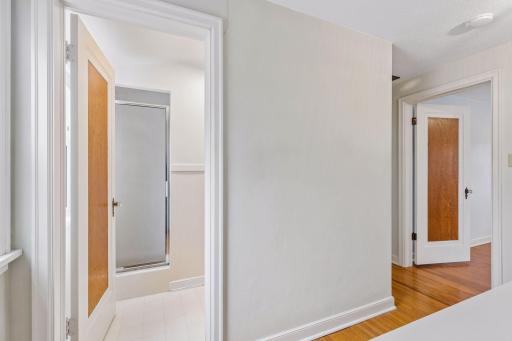 Full-height upper-level hallway leads to a 3/4 bath and 2 other bedrooms.