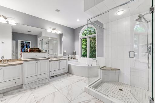 En-suite full bathroom in primary bedroom with walk-in closet with organizational components