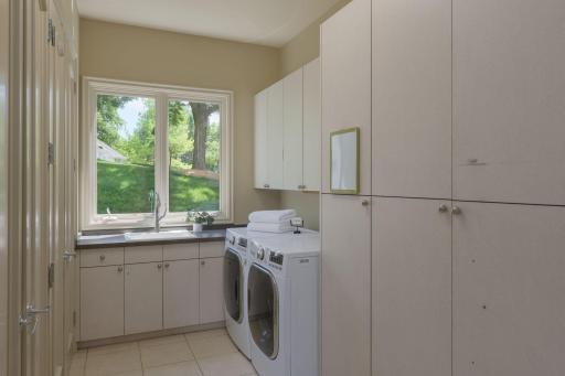 Even daily routines feel elevated in this bright laundry room, complete with abundant cabinetry, workspace, and scenic views of the surrounding landscape.