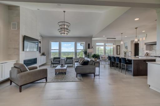 The sun-drenched main level showcases an expansive open-concept design enhanced by soaring vaulted ceilings, Andersen windows, stunning engineered wood floors, and picturesque views at every turn.