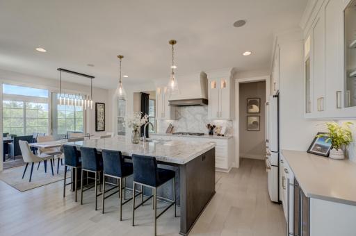 The chef’s kitchen is equally captivating, featuring Cambria countertops, an oversized center island, premium appliances, a beverage fridge, reverse osmosis system, and a walk-in pantry.