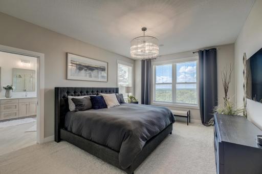 A luxurious owner's retreat offers a private sanctuary featuring expansive windows, a spa-inspired bath with heated floors, a jetted tub, a walk-in shower, dual vanities, and an impressive walk-in closet with custom organization systems.
