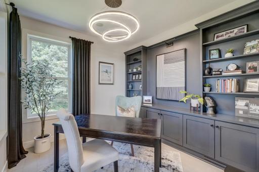 A dedicated office with custom cabinetry and built-in shelving offers a refined workspace.