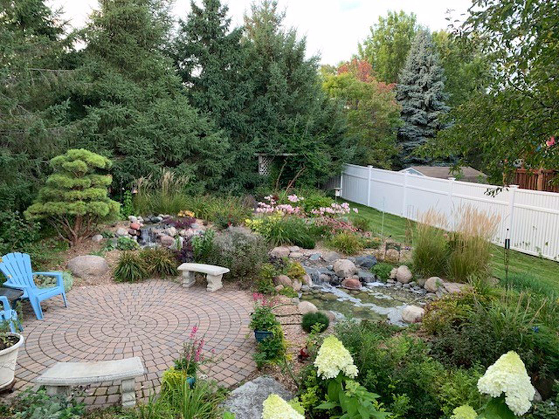 Stunning summertime views of the professionally landscaped backyard with water feature!