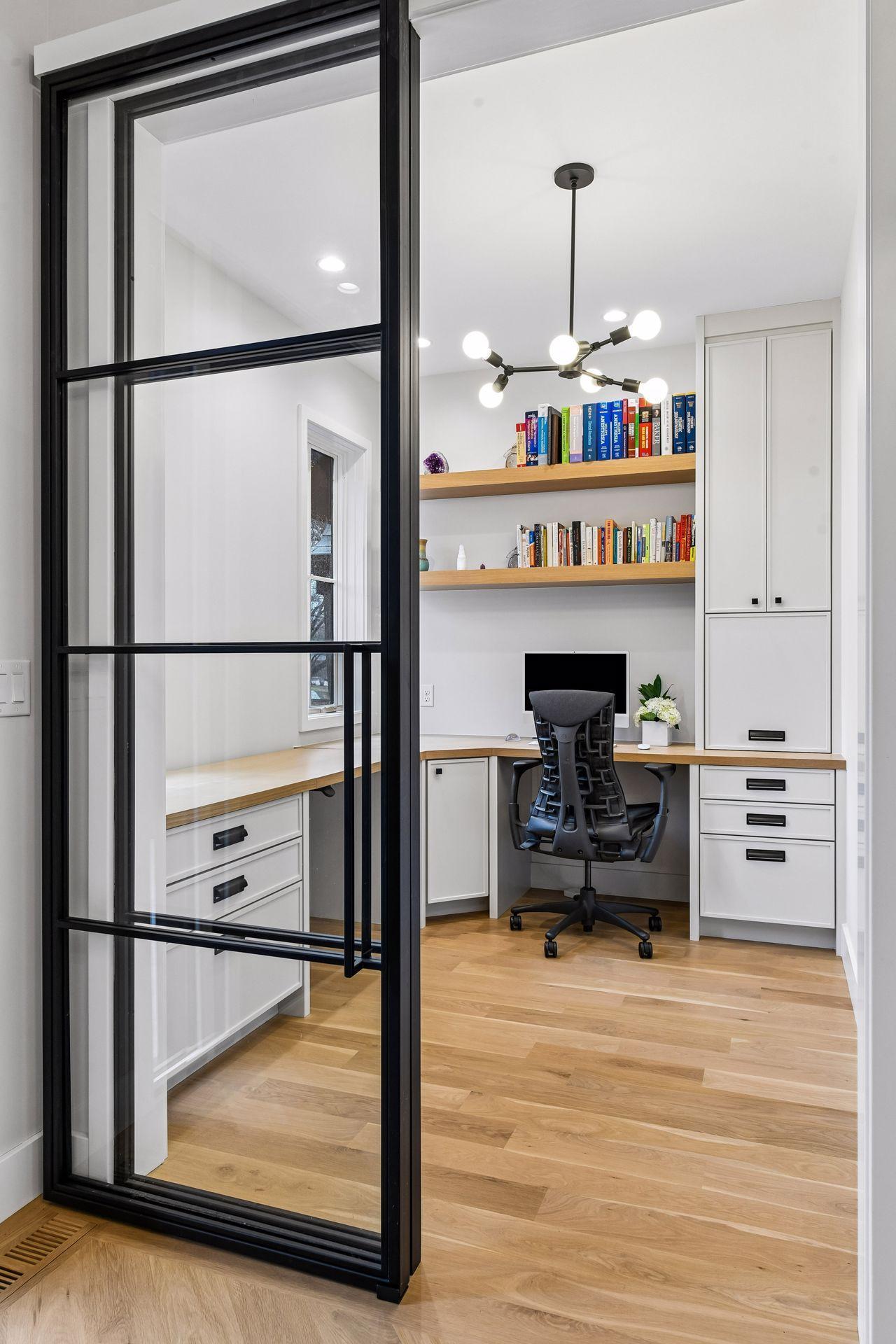 Office with built in desk and custom cabinetry by Century Cabinets, Millwork by Makers and Iron sliding glass doors by BiltFab.