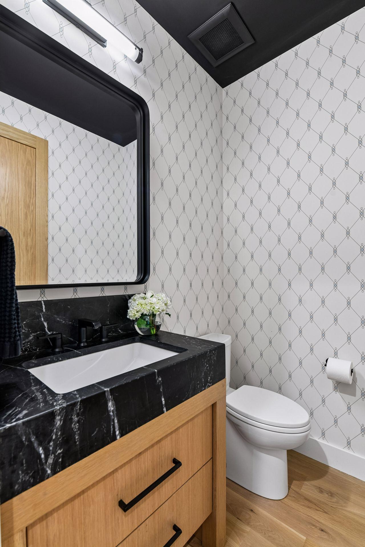 Schumacher wallpaper with natural stone topped custom vanity in the half bath on the first floor .