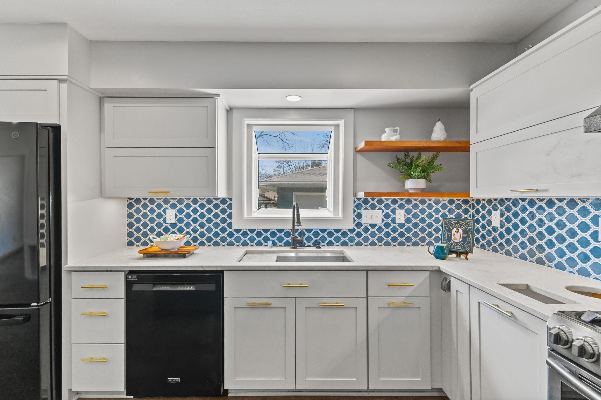 Bright kitchen featuring stylish tile backsplash and ample cabinetry