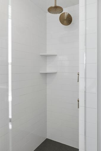 Large shower in primary bath with two shower heads, ceramic tile walls, floor & ceiling plus frameless shower door (photo of actual listing).