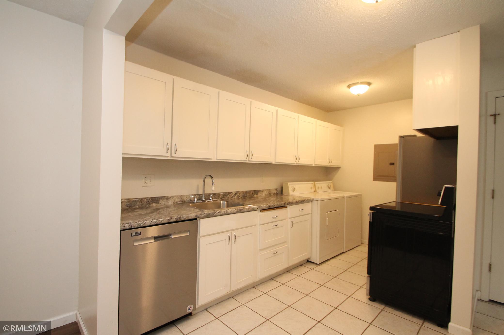 The kitchen features newer cabinetry and stainless steel appliances. Tile floor.