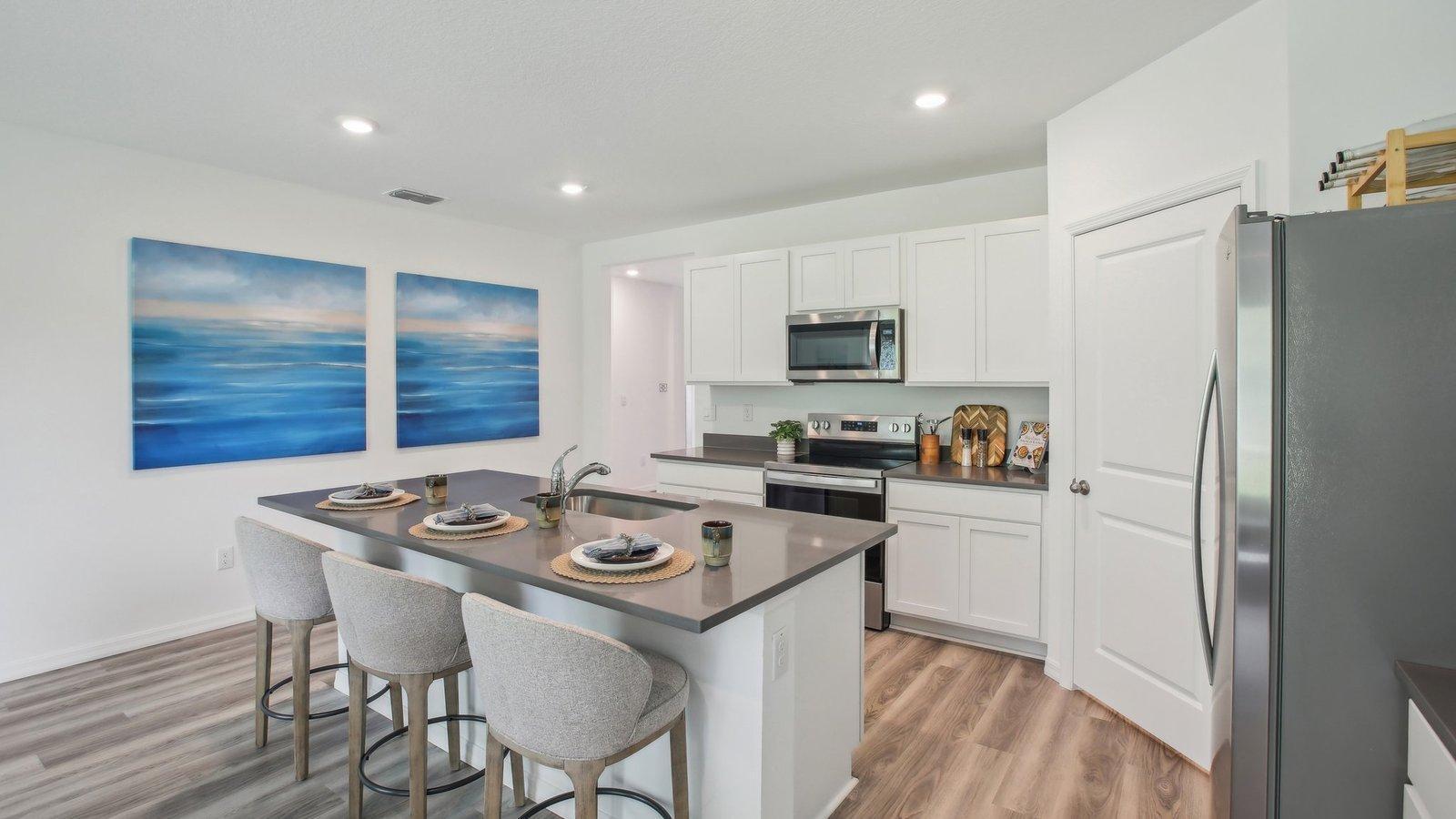 Ample space for seating at the kitchen island. Actual home will include a tile backsplash, quartz countertops, cabinet hardware, soft close drawers and more!