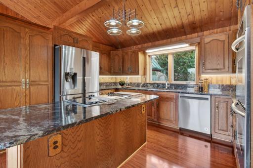 The kitchen features a center island and a vaulted, beamed ceiling. Ample cabinetry, under cabinet lighting and stainless steel appliances complete the space.