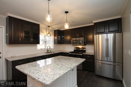 Updated kitchen features a granite center island and countertops and stainless steel appliances.