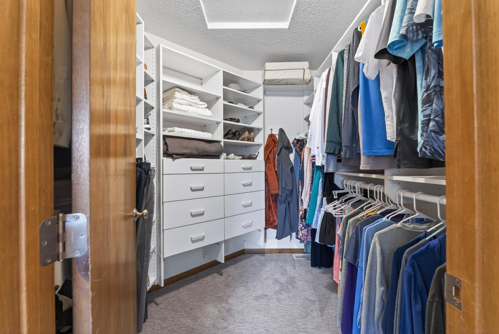 Primary suite walk-in closet with built-in storage system.