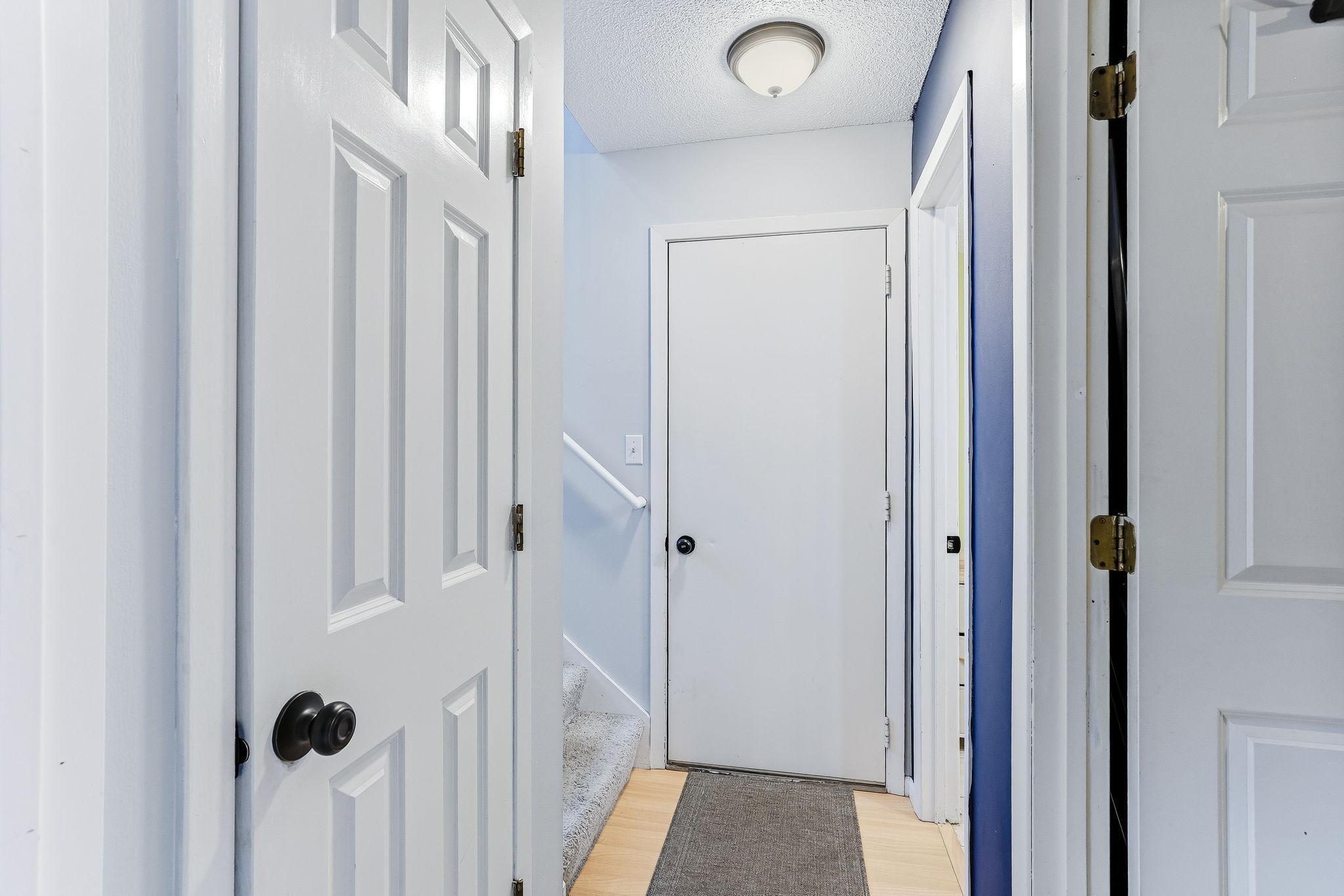 Clean and functional hallway connecting living spaces, with easy access to stairs and additional rooms.